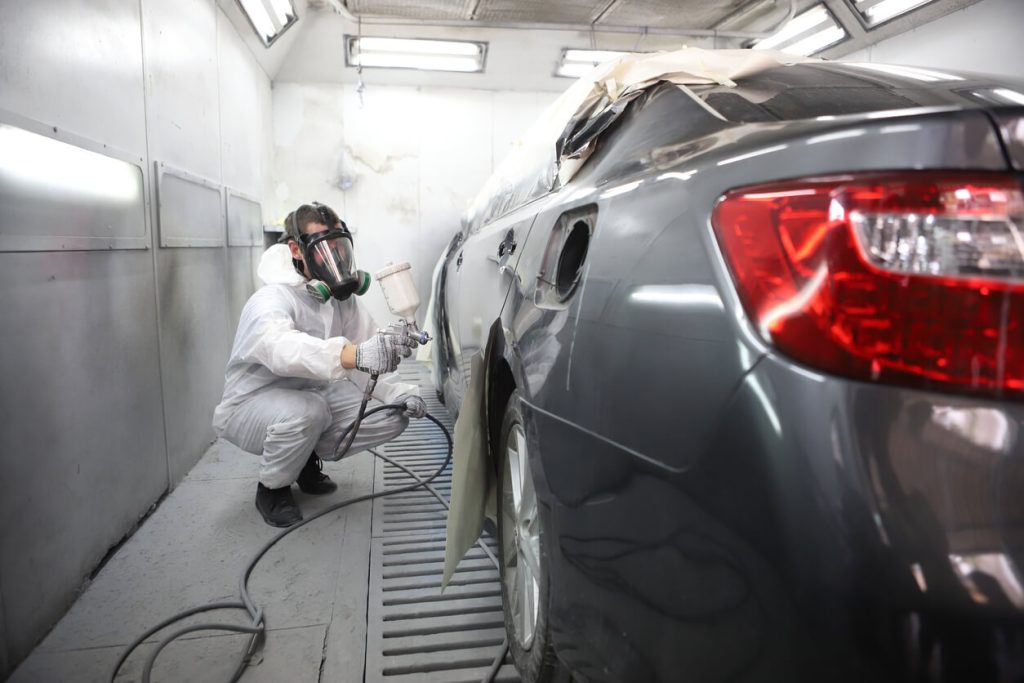 Accident repair center showing a man repainting a car